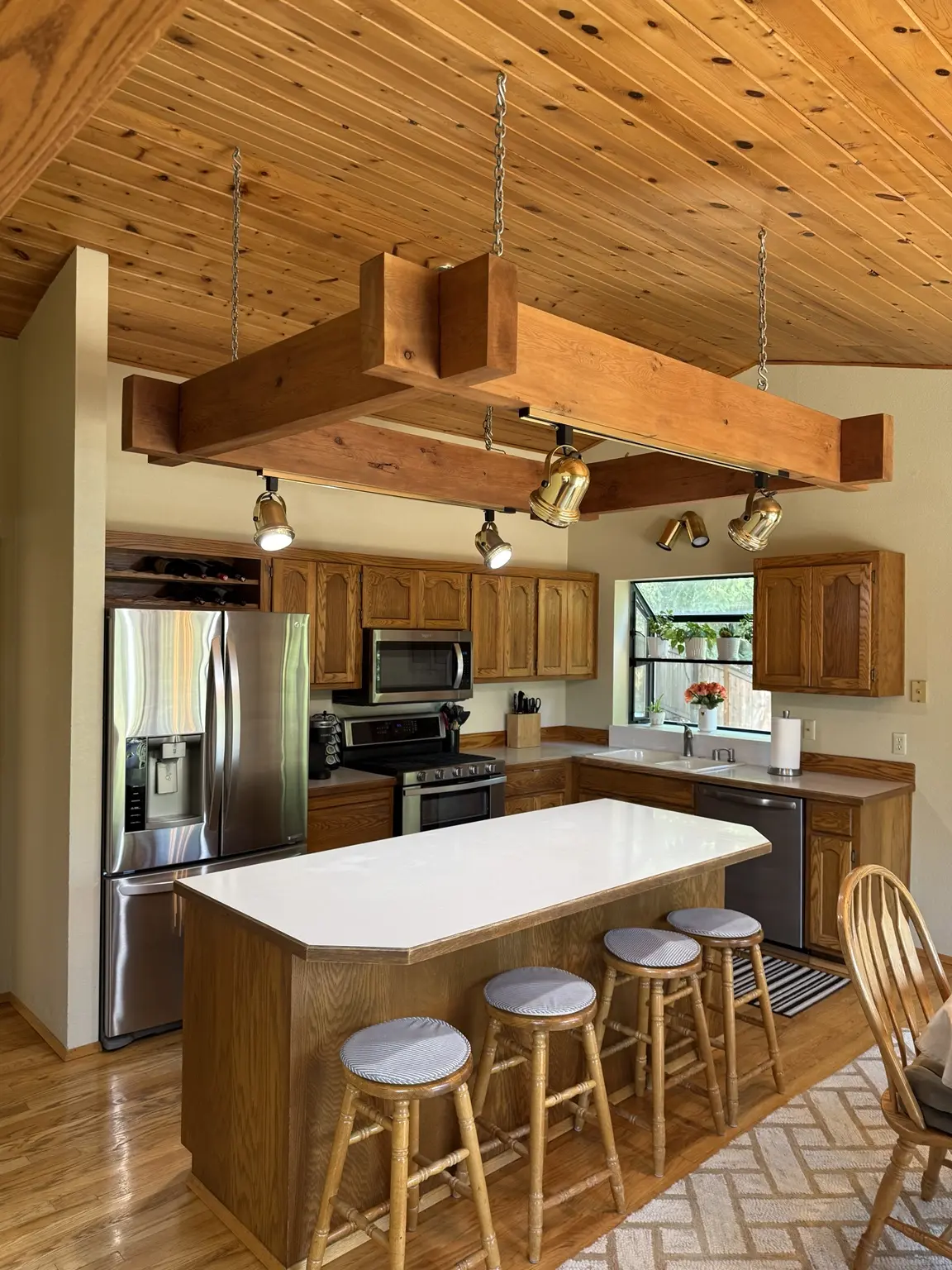Kitchen before remodeling with natural oak cabinets and light countertops
