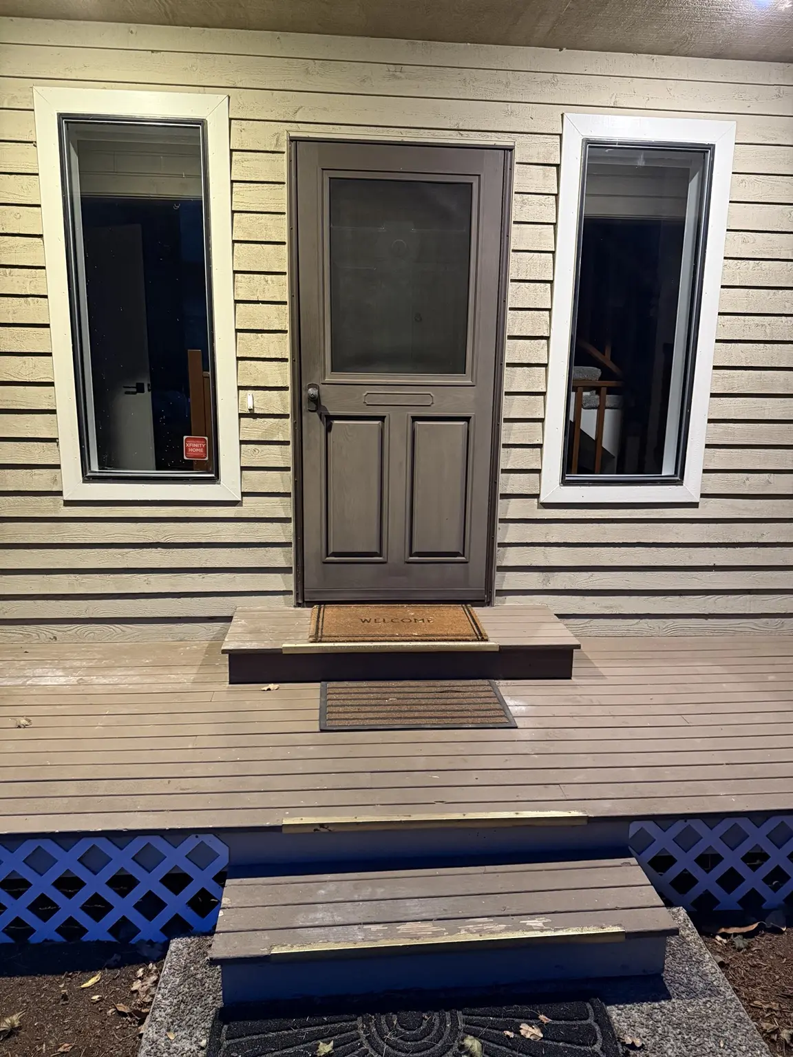 Original tan front porch with white window trim, brown screen door, brass stair edges and lattice