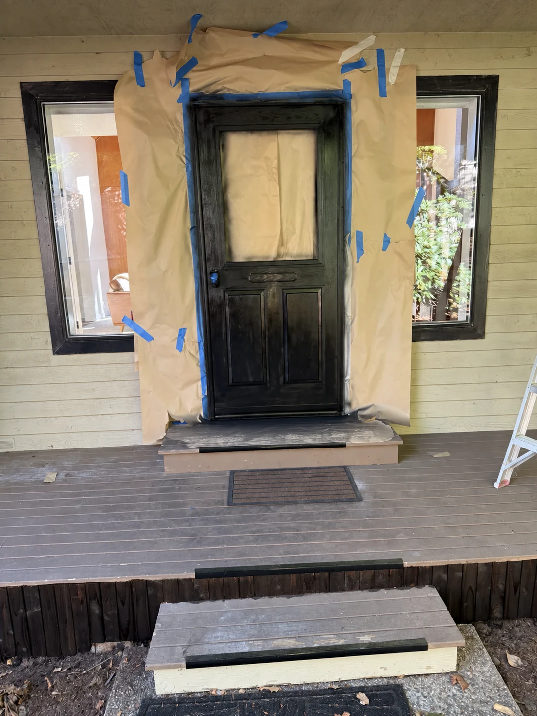 Black front door and trim being painted while the walls are masked