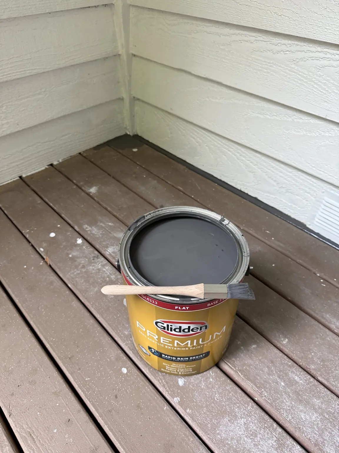 Open can of Glidden Premium exterior flat paint with a trim brush