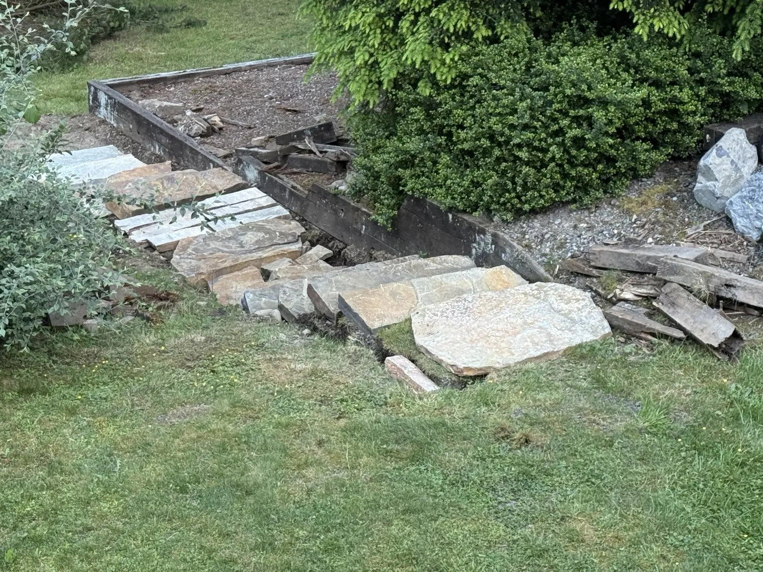 Stone steps under construction beside deteriorated landscape timbers