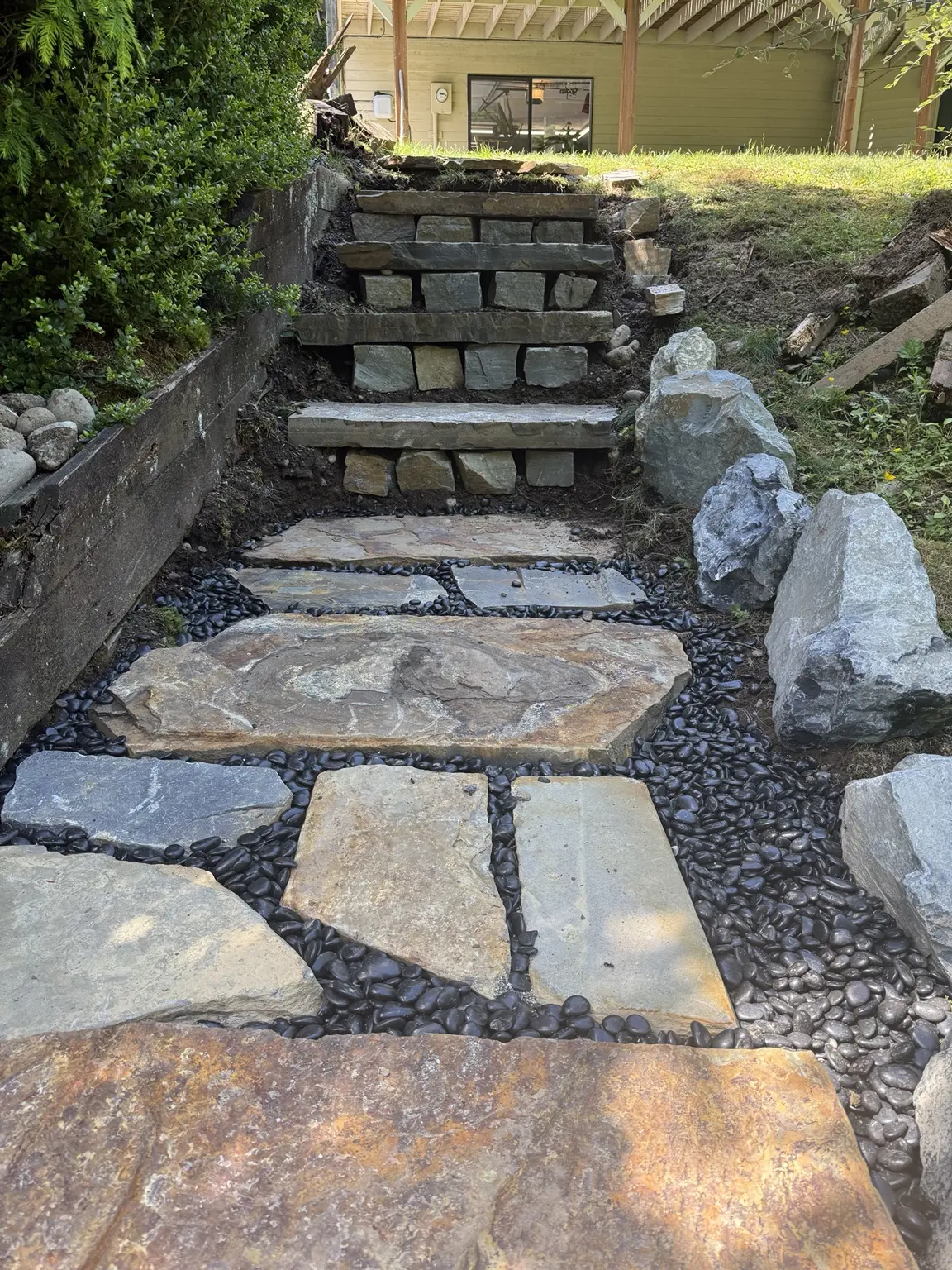 Stone landing finished with dark rounded drainage rock between the slabs