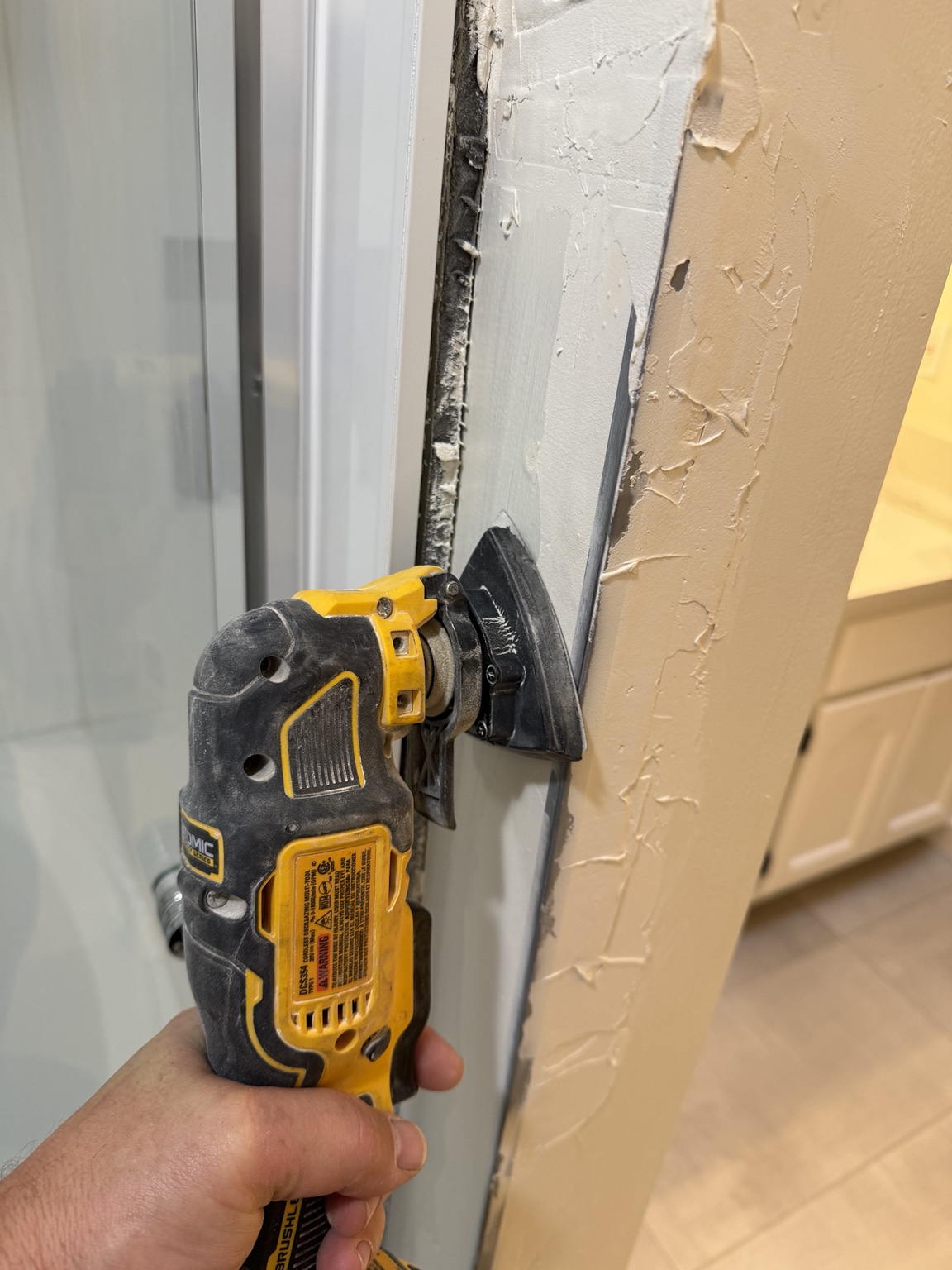 Removing loose wall material beside the shower with an oscillating tool